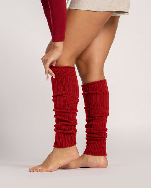 Close-up of red ribbed wool leg warmers worn barefoot, showing soft knit texture and slouchy fit.