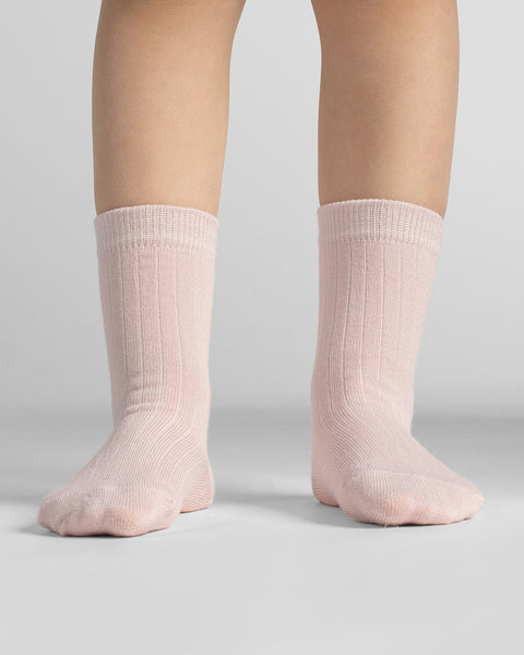 Close-up front view of bare legs standing straight, wearing ribbed light pink crew socks against a neutral background.
