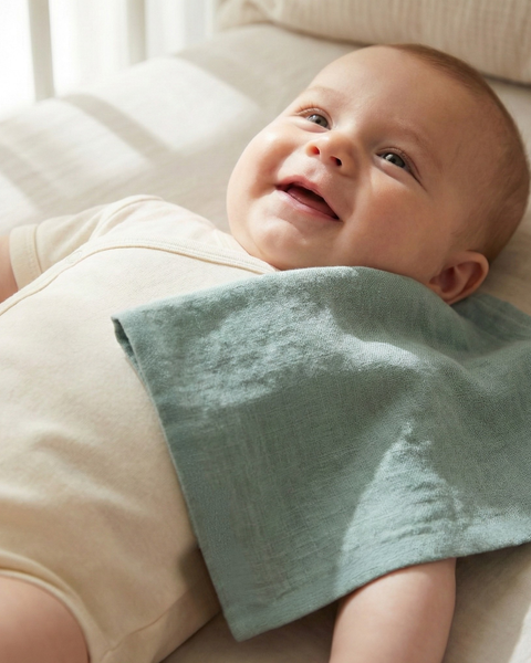 Mint green linen baby burp cloth draped over infant during cuddle time, lightweight breathable baby essential for feeding and burping