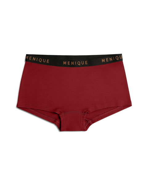 A product shot of deep red (royal cherry) women's boxer briefs laid flat against a plain white background. The underwear features a black elastic waistband with the brand name "MENIQUE" woven repeatedly in bronze lettering.