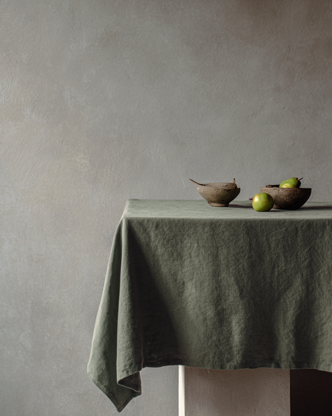 Stone green linen tablecloth with minimalist natural décor and textured ceramic bowls.