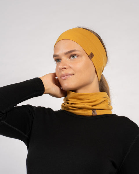 Side view of woman wearing yellow Merino wool headband and gaiter set for outdoor comfort