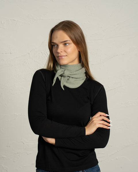 Woman wearing light green cashmere Merino wool bandana tied as neck scarf.