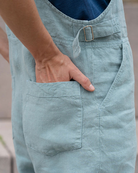 Close-up of a woman's hands inside linen jumpsuit back pockets.
