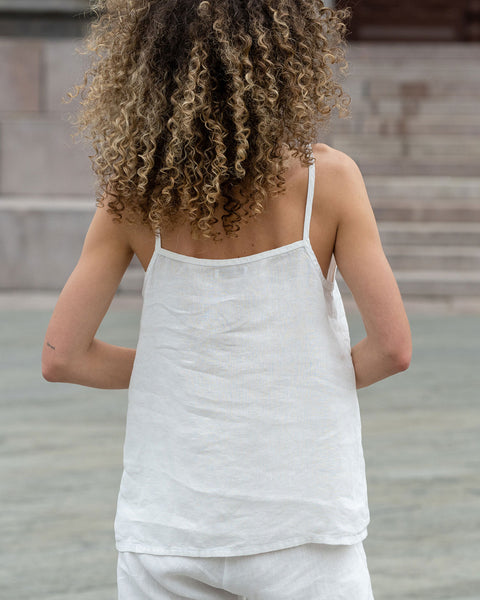 Beautiful woman posing from the back in a city. Wearing pure white linen slip top and pure white linen pants.