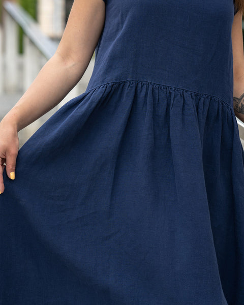 Close-up of a girl holding her linen dress cecilia in a storm blue color.