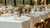 A wedding table with a white linen tablecloth and white linen napkins. THere are glassess and flower centerpieces in the middle of the table. 