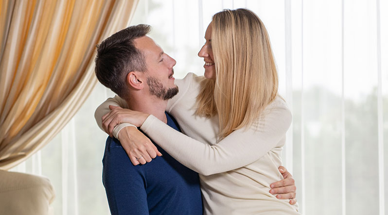 In the photo you can see couple hugging. They are both wearing long sleeve sweaters made from soft and organic 100% Merino Wool. Woman is wearing natural color crewneck, while man is wearing dark blue one,
