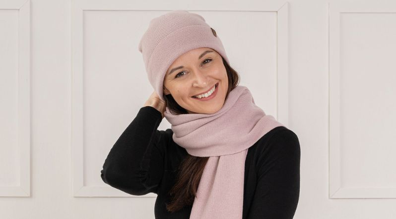 Smiling woman wearing dusty pink cashmere scarf and beanie