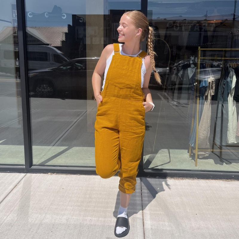 A young woman wearing a spicy yellow pinafore jumpsuit NICCI.