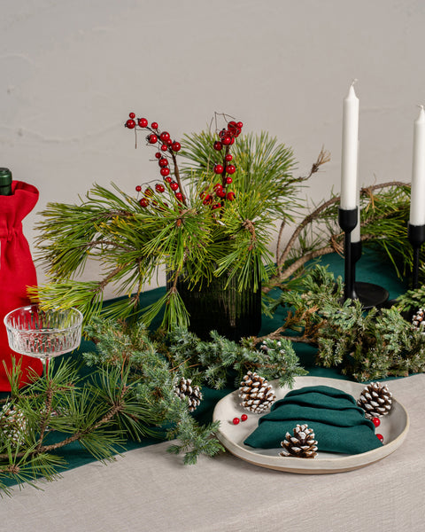 The menique linen tablecloth in natural color. The tablecloth drapes over a wooden table