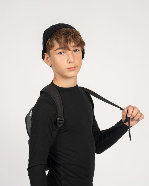 boy holding the backpack for school with menique merino wool midweight thermal shirts in black color