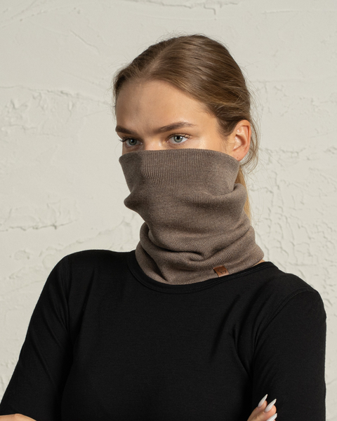 Woman wearing a brown knit Merino wool neck gaiter pulled over nose, winter face warmer for cold weather.