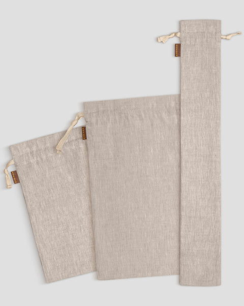 Three natural linen fabric bags with drawstrings on a light gray background