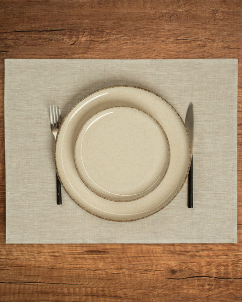 The menique linen placemat in natural color on a wooden table top.