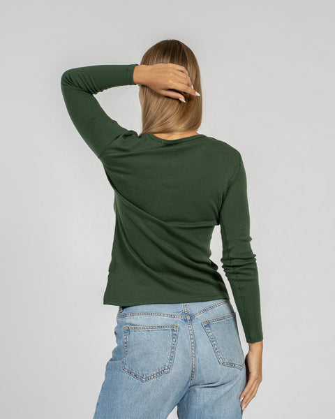 The menique women&#39;s merino wool dark green long sleeve top matched with classic light blue jeans, back view.