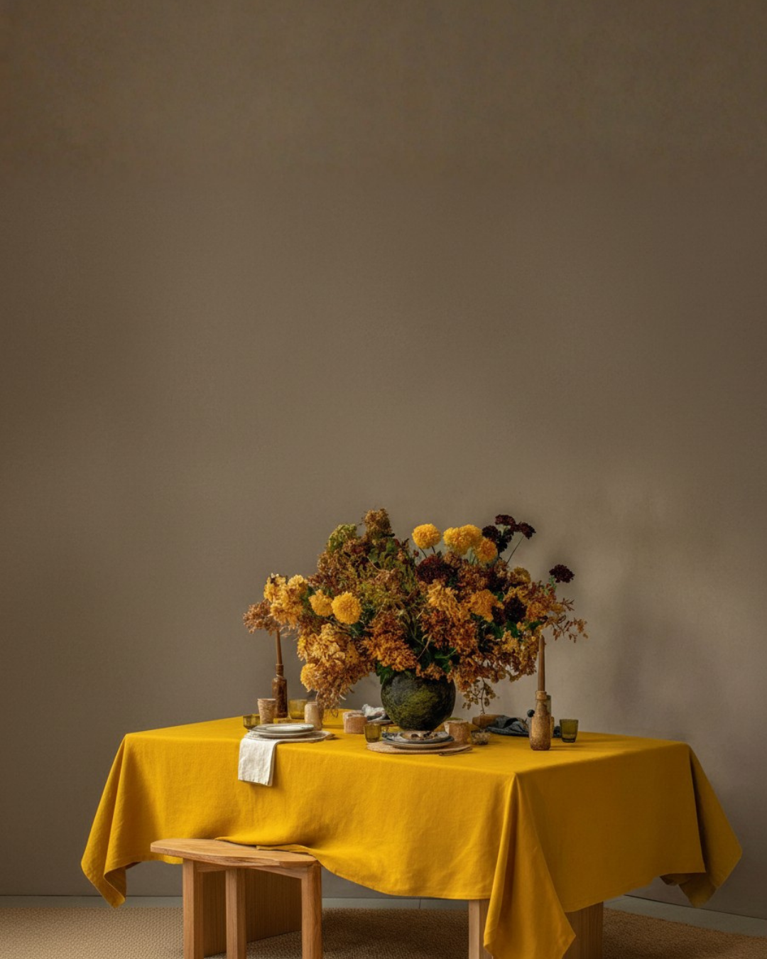 Linen tablecloth in mustard yellow on a dining table with autumn floral arrangement