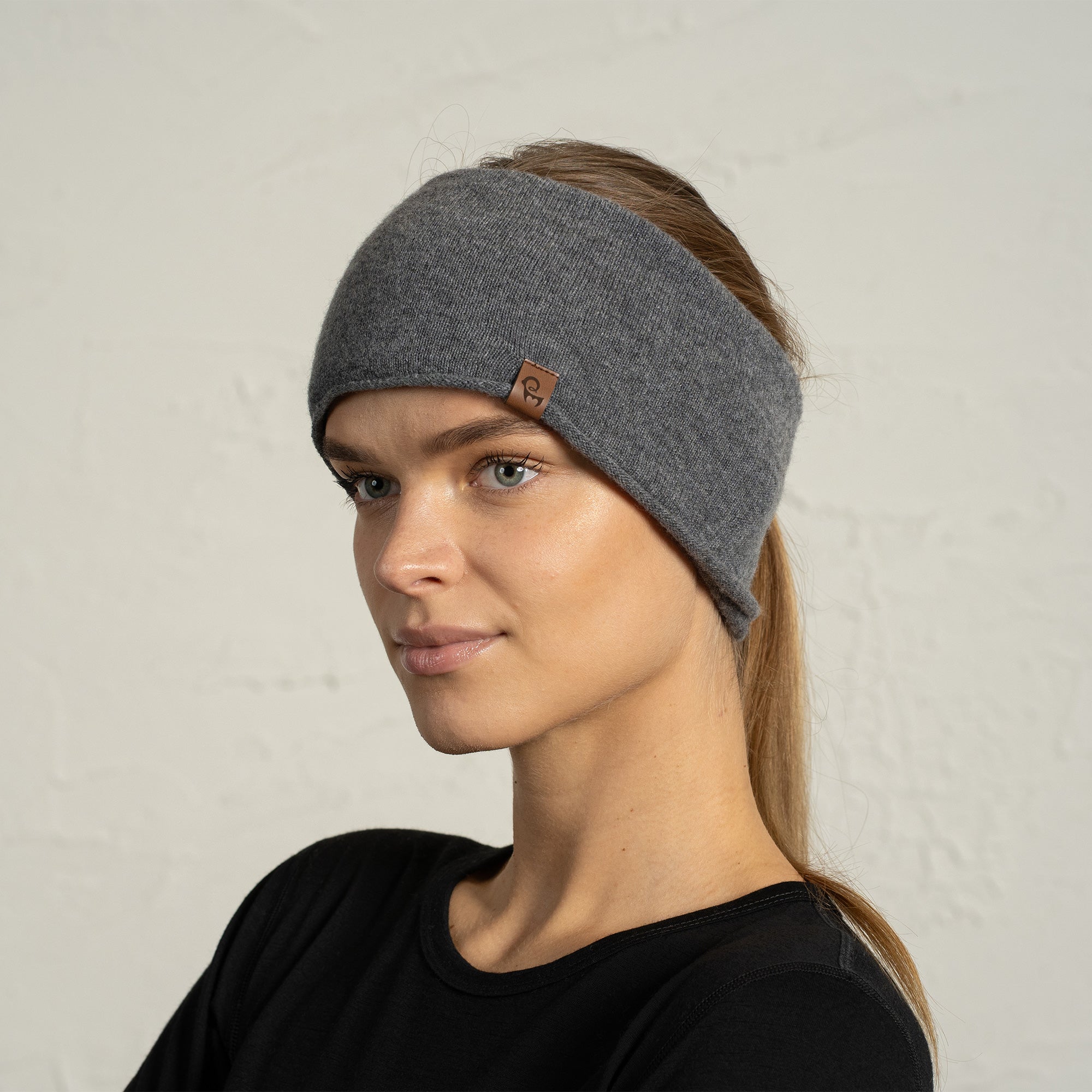 Woman wearing a beige merino wool neck gaiter, standing with arms crossed and looking at the camera.