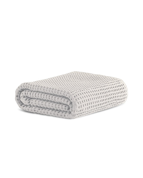 A neatly folded, white waffle-weave towel isolated on a pure white background. The textured waffle pattern is clearly visible.