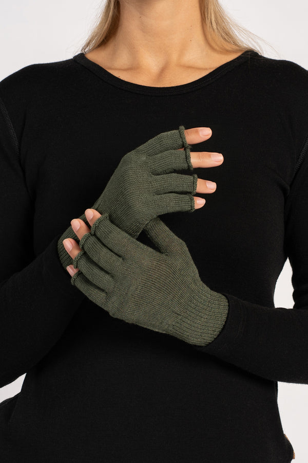 Frontal view of a woman in a black top modeling dark-green fingerless gloves, one hand raised and the other clasping it.