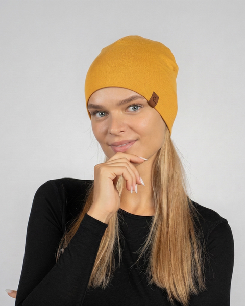 Woman wearing yellow merino wool liner beanie, lightweight breathable wool hat for everyday wear and outdoor activities.
