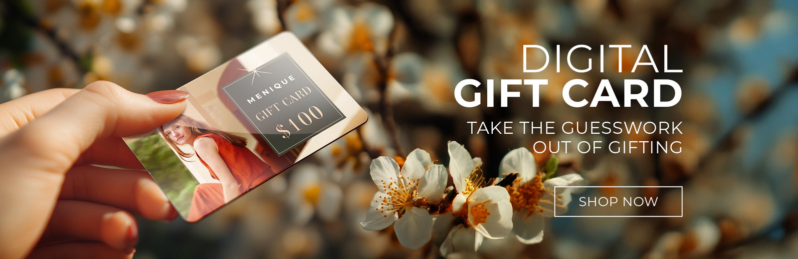 A hand holding a $100 digital gift card with a photograph on it, against a blurred floral background. The image also includes promotional text and a "SHOP NOW" button.