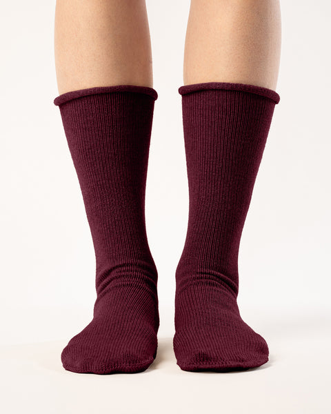 A person is shown from the mid-thigh down, wearing ribbed, royal cherry colos socks. The socks are pulled up to the mid-calf, and the person&#39;s feet are slightly apart against a plain white background. The lighting is even, highlighting the texture of the socks.