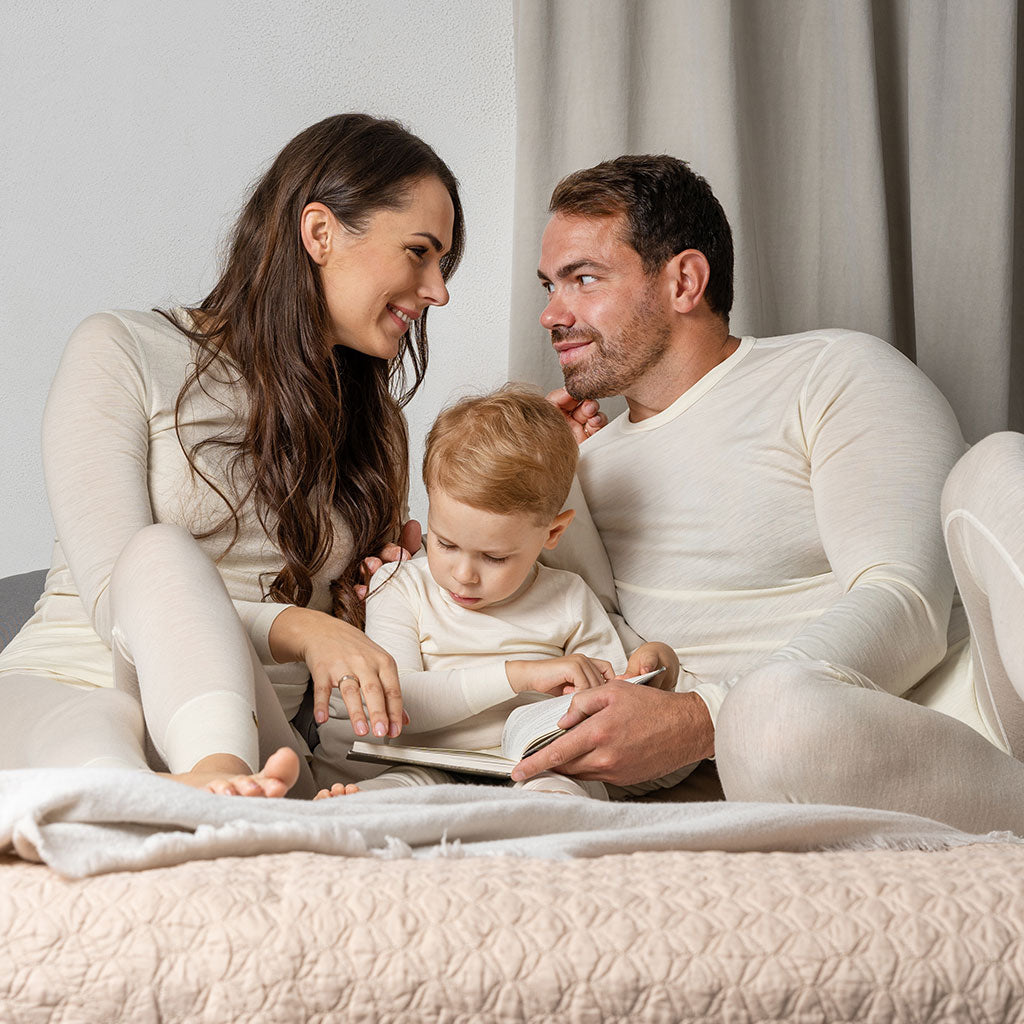 Family on the bed wearing matching pajamas from Merino wool