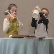 Kids playing with kitchen tools while wearing linen aprons