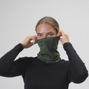 Woman puts Merino wool neck gaiter in dark green color on her face