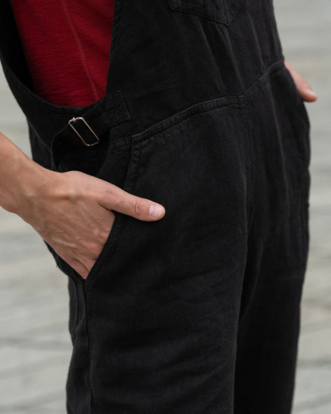 Close-up of a woman putting her hands in to pure black linen jumpsuit pockets.