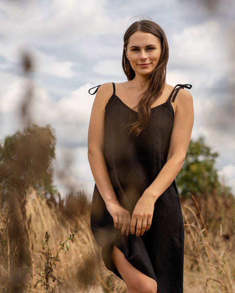 Woman standing outdoor and wearing a Liv slip dress made from linen in black color