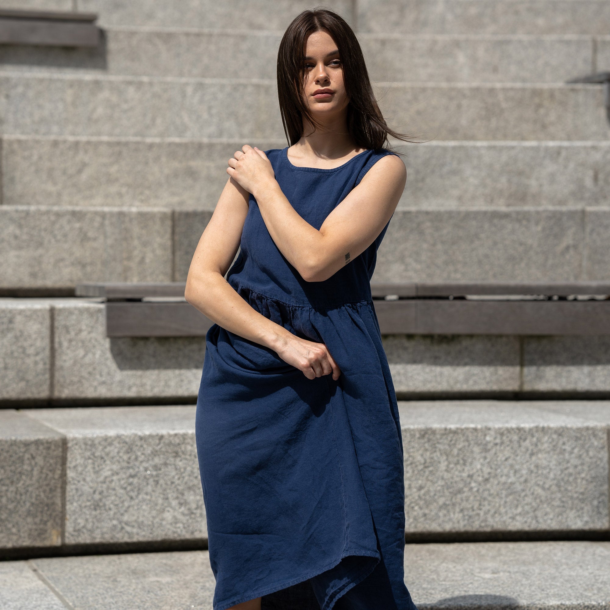 Young woman posing in a city, wearing linen smock dress Maya in a Storm blue cover.