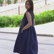 Young woman posing in a city, wearing linen smock dress Maya in a Storm blue cover.