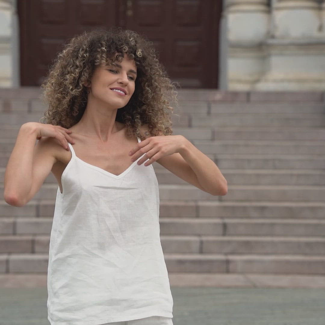 Beautiful woman posing in a city. Wearing pure white linen slip top and pure white linen pants.